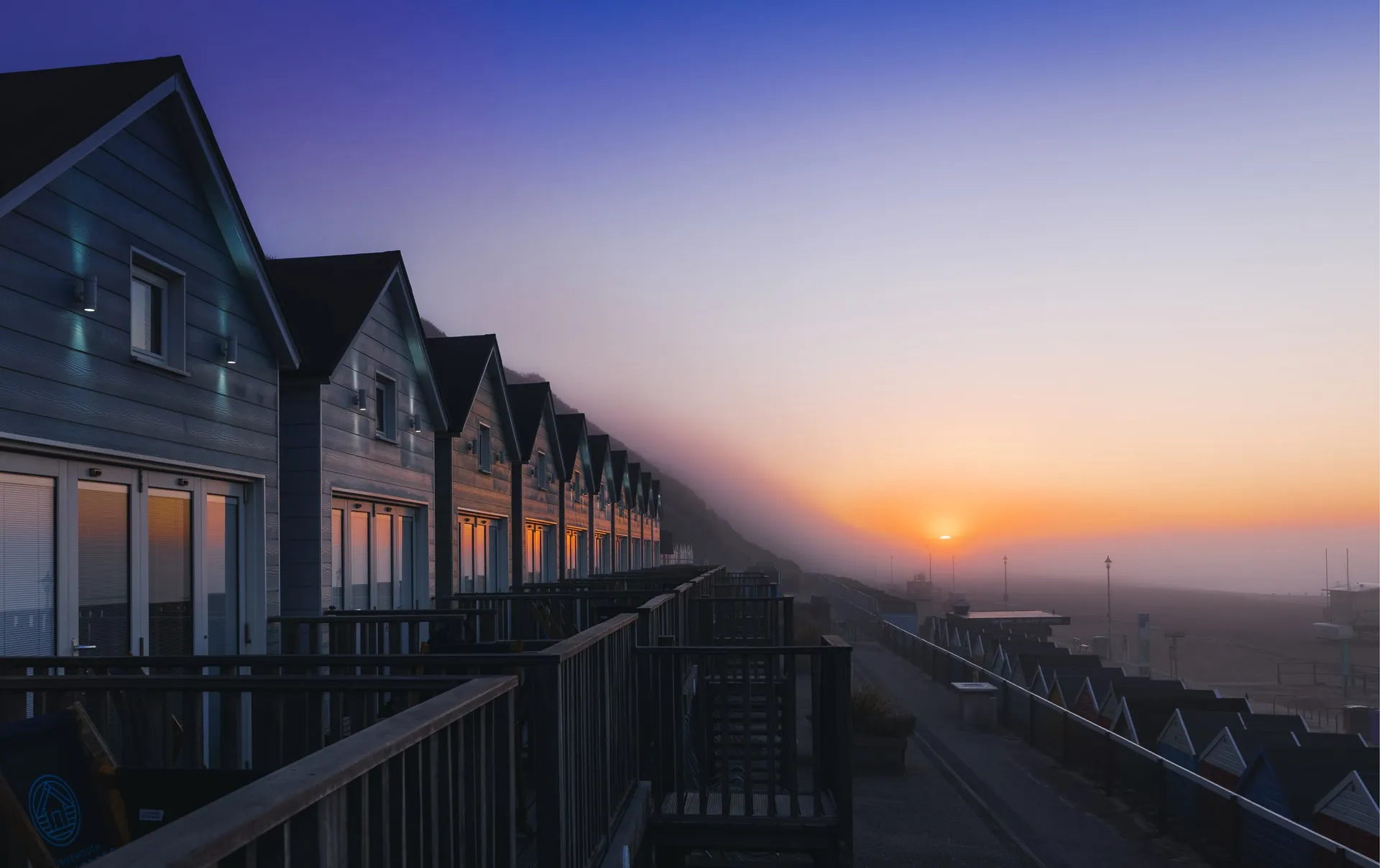 Morning sunrise reflections over row of Beach Lodges