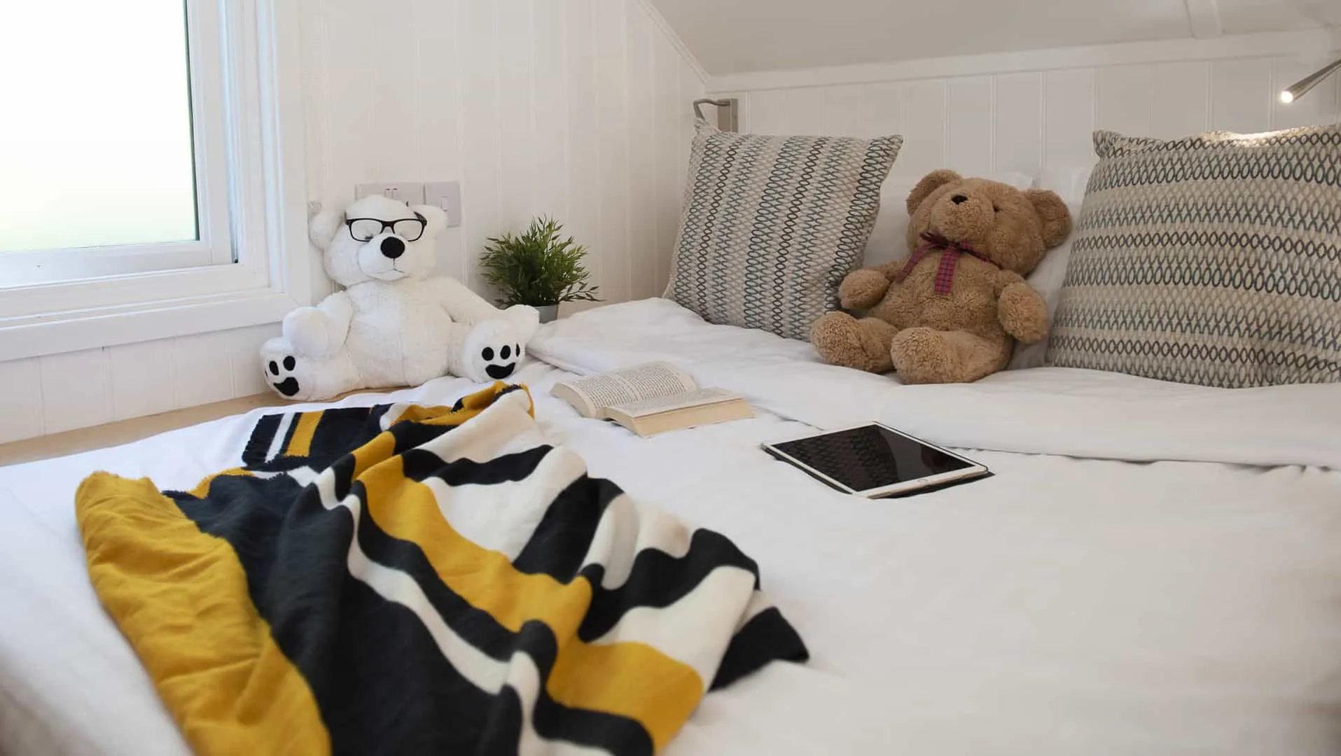 Beach lodge bed with items on such as a teddy beach, ipad and scarf